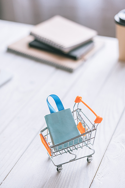 selective focus of decorative shopping bag in cart on wooden desk