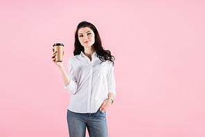 attractive woman holding disposable cup of coffee, isolated on pink