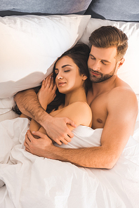 beautiful nude couple embracing while sleeping in bed
