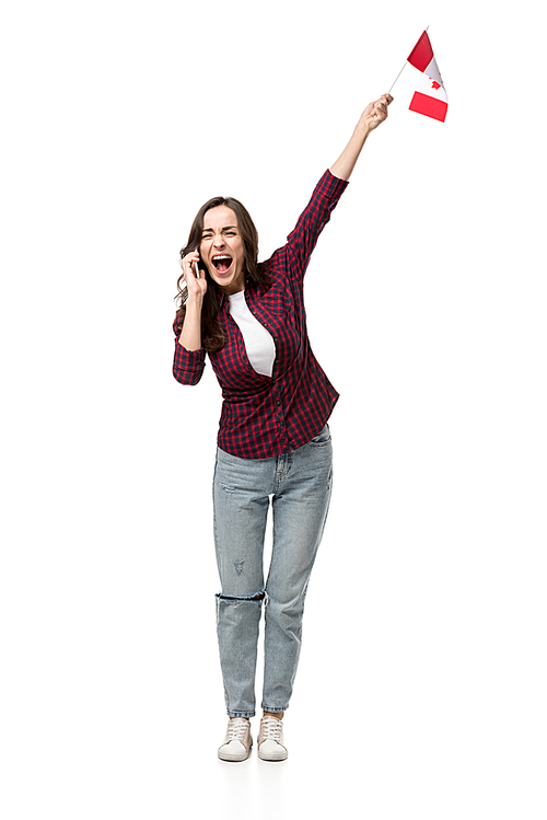 excited woman in casual clothes holding canadian flag and talking on smartphone isolated on white