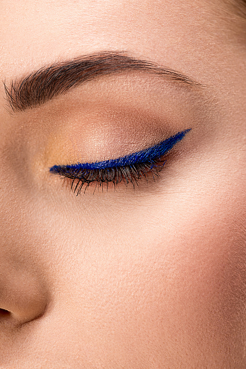 partial view of closed female eye with blue eyeliner and perfect skin