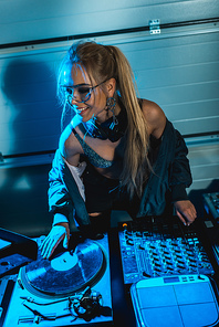 stylish blonde dj woman smiling while touching vinyl record