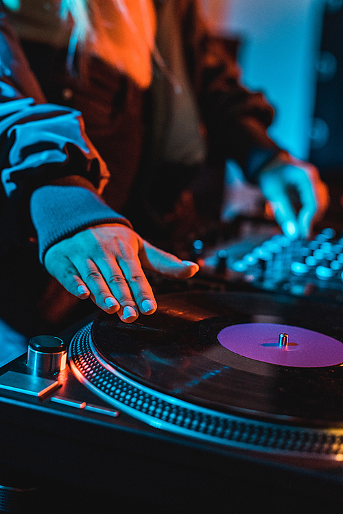 cropped view of dj woman touching vinyl record in nightclub