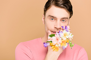 man covering face with flowers on hand isolated on beige
