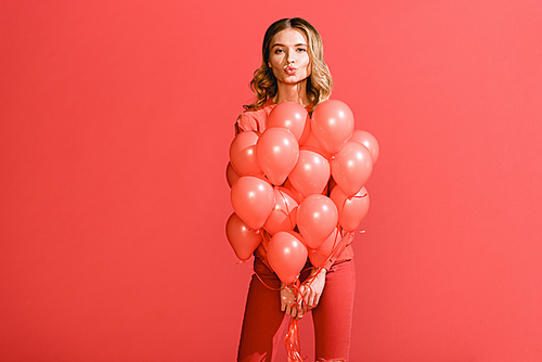 attractive girl making air kiss and posing with living coral balloons. Pantone color of the year 2019 concept