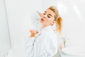 beautiful woman in white bathrobe playing with hair and  in bathroom