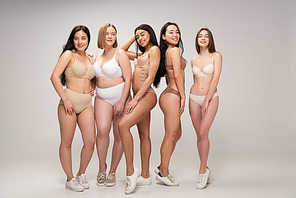 five smiling multiethnic girls smiling and posing at camera, body positivity concept