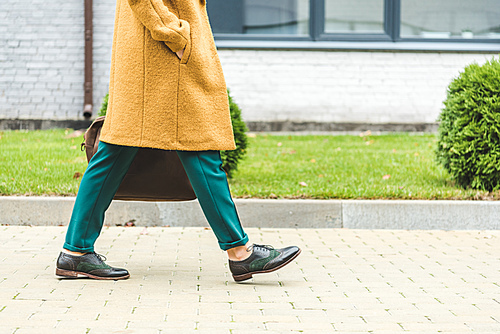 cropped view of woman in yellow coat walking in park