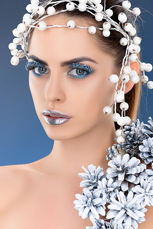 portrait of beautiful charming woman with hair accessory, christmas pine cones, winter makeup and glitter, isolated on blue