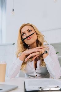 businesswoman grimacing and making mustache with pen