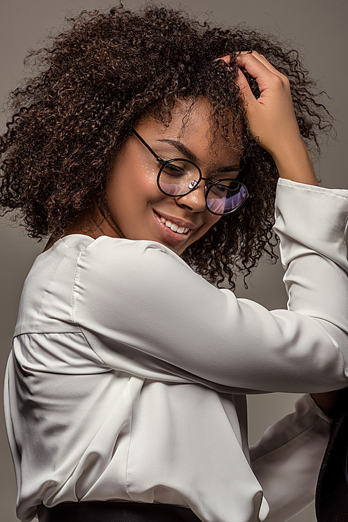 Young smiling african american woman in white shirt wearing glasses isolated on grey background