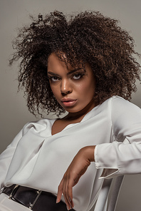 Young african american woman with seductive look in white shirt isolated on grey background