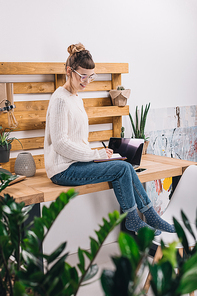 smiling girl sitting on table in office and writing something to notebook