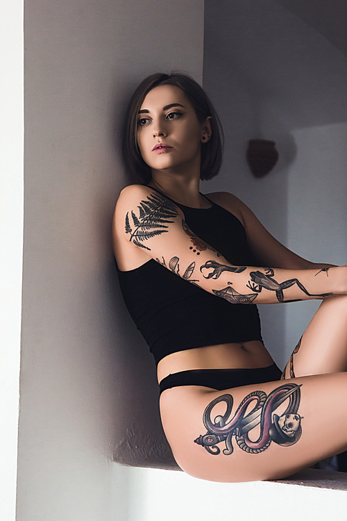 beautiful tattooed girl in underwear sitting and looking away