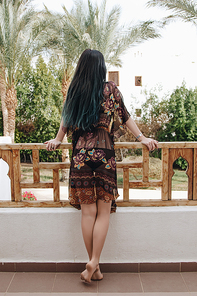 back view of barefoot girl leaning at railing and looking at beautiful resort in Egypt