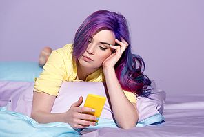 bored young woman using smartphone in bed