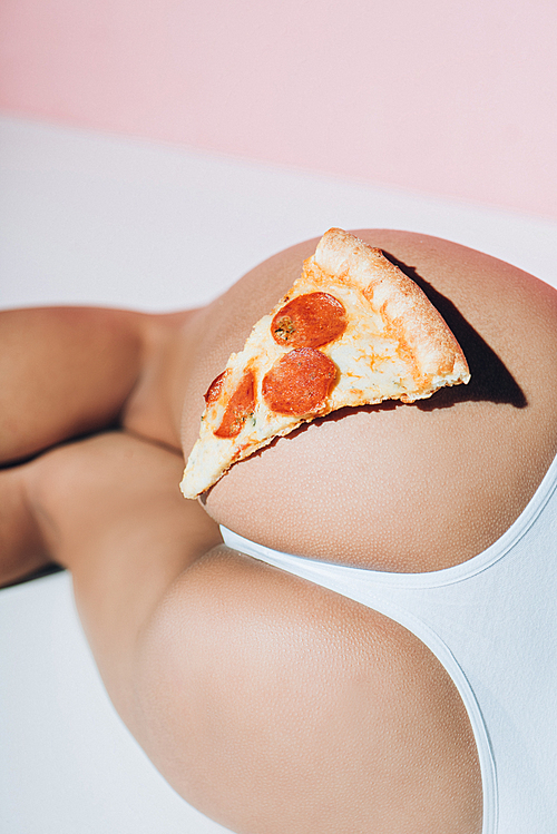 partial view of piece of pizza on female booty