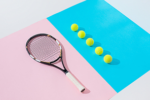 tennis racket on pink and yellow balls in row on blue