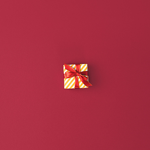 top view of festive decorated christmas gift with ribbon on red surface
