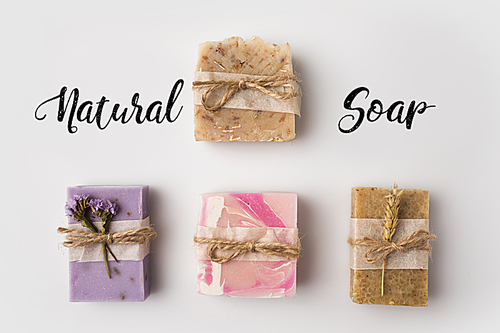 top view of different handcrafted soap with natural soap lettering on white surface