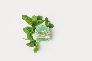 top view of handcrafted mint soap with leaves on white surface