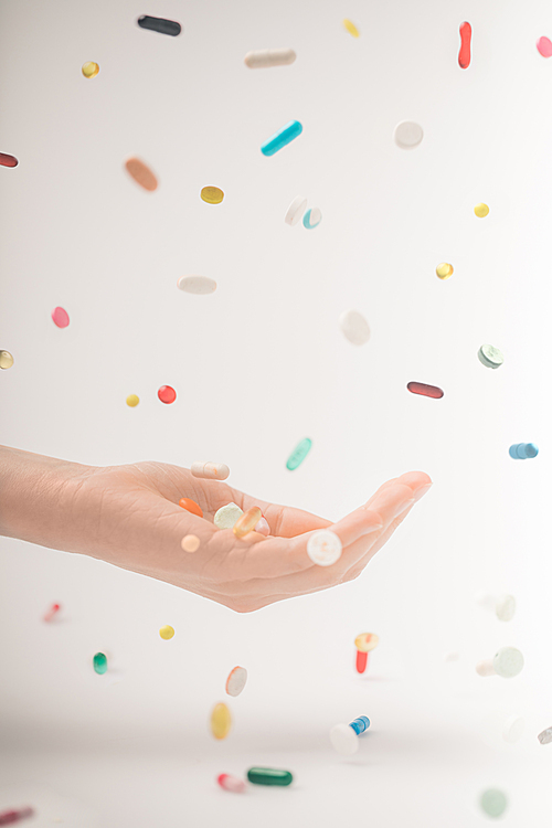 Cropped image of female hand catching colored falling pills