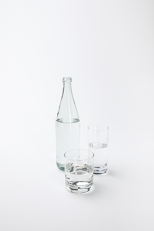 two different glasses and bottle with calm water isolated on white