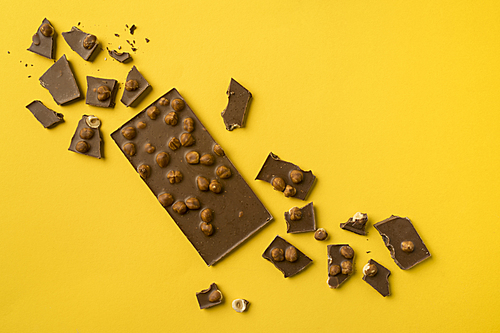 Top view of Chocolate bar with scattered pieces isolated on yellow