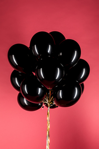 close up view of black shiny balloons isolated on pink