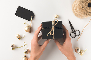 cropped view of female hands holding black christmas present, isolated on white
