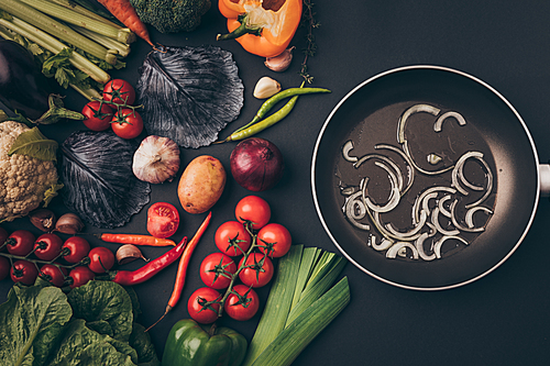 top view of colored vegetables and frying pan on gray table