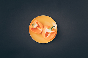 top view of two halves of yellow bell pepper on yellow plate on gray