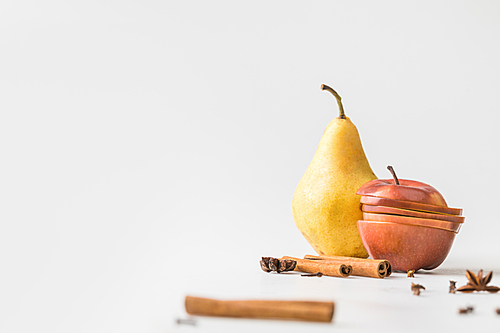 close-up shot of apple and pear with spices on white surface