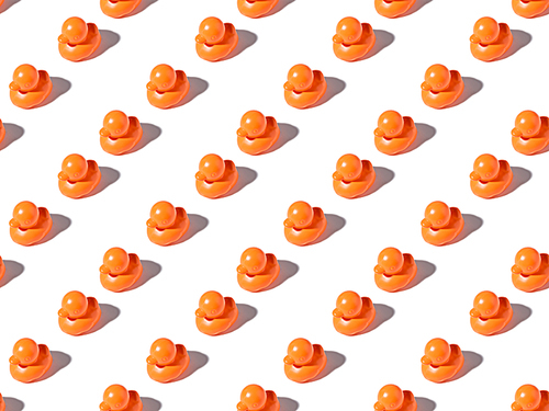 seamless pattern of small orange rubber ducks on white