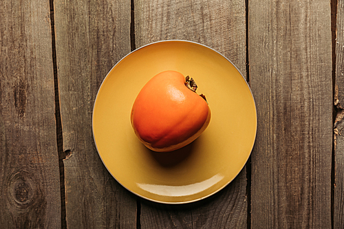 top view of persimmon on yellow plate on wooden table