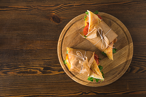 top view of two delicious panini on cutting board on wooden table