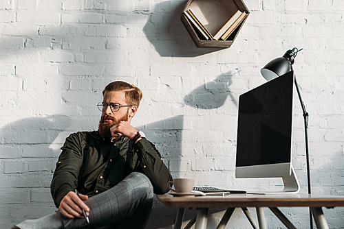 pensive handsome businessman sitting in chair in office