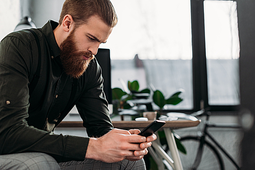 handsome businessman sitting and looking at smartphone