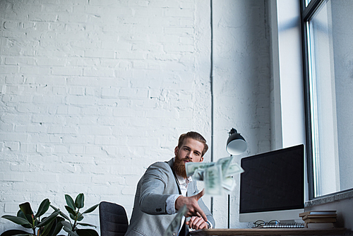 handsome businessman throwing dollars in office