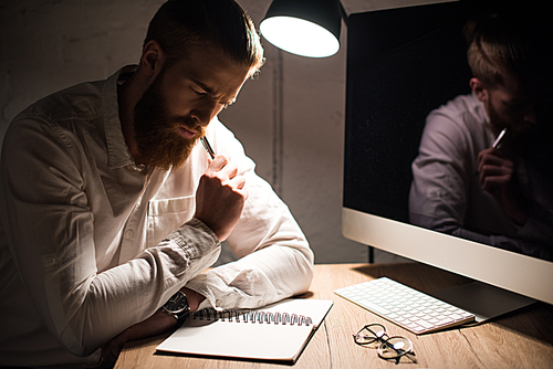 thoughtful businessman working in office in evening with notebook