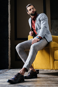 handsome stylish man in glasses and suit sitting on couch