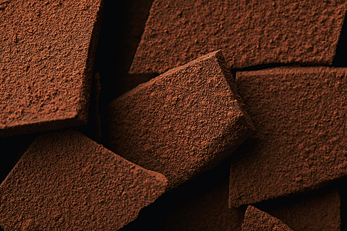 close up view of heap of chocolate bars in cocoa powder