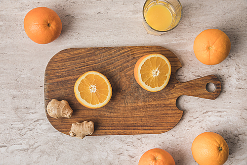 top view of cut orange and ginger on wooden board