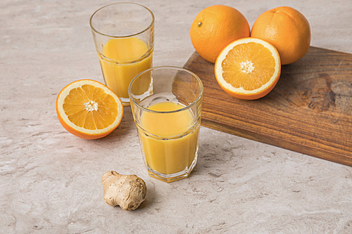 high angle view of homemade orange juice and oranges with ginger on marble table