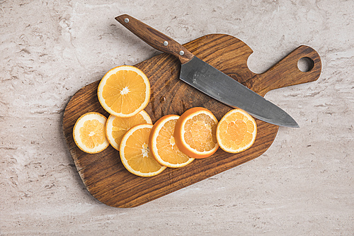 top view of cut oranges and knife on wooden board