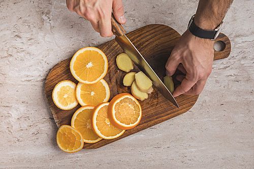 cropped image of man cutting ginger on wooden board