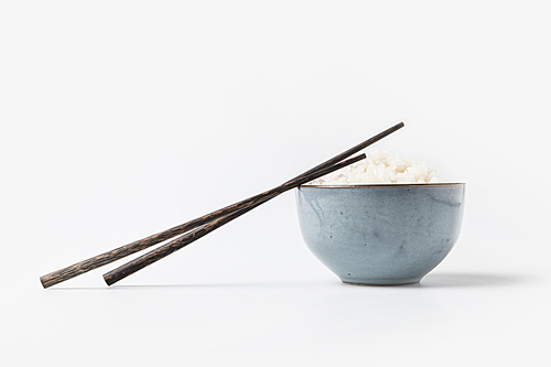 bowl of tasty rice with chopsticks on white tabletop
