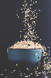 close-up shot of rice spilling into bowl on black table