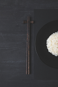 top view of rice and chopsticks on black table