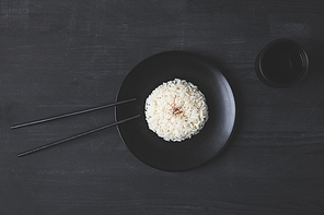 top view of rice on plate with chopsticks on black table